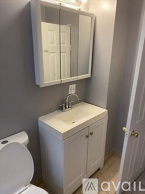 Brockton apartment for rent - A white bathroom with a toilet, sink and mirror.