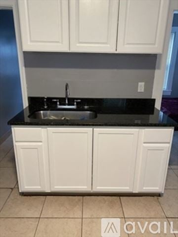 Brockton apartment for rent - A kitchen with white cabinets and a black countertop.