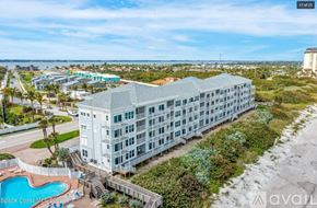 Melbourne Beach condo for rent - A large white building with a pool in front of it.