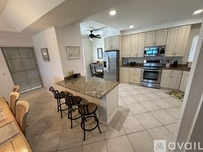 Melbourne Beach condo for rent - A kitchen with a granite countertop and a dining table with chairs.