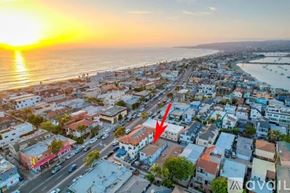 San Diego condo for rent - A sunset view of a coastal town with a red arrow pointing to a specific building.