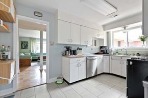 Richmond house for rent - A modern kitchen with white cabinets and a black stove top.