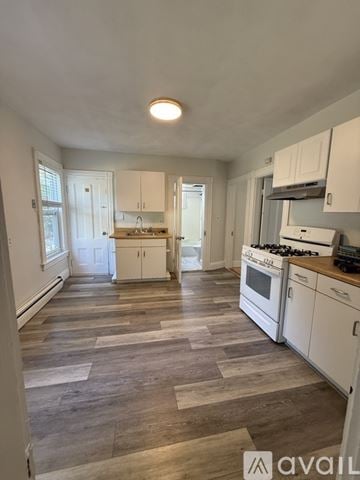Newton apartment for rent - A kitchen with white cabinets and a wooden floor.