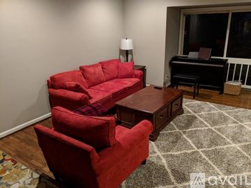 Rockville apartment for rent - A living room with a red couch and a piano.