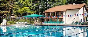 Rockville apartment for rent - A large swimming pool in front of a house with a deck and sunshades.