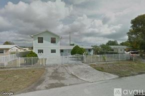 Miami Gardens house for rent - A white house with a grey fence in front of it.