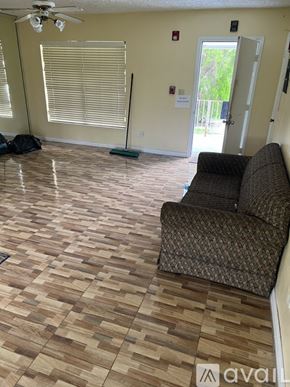 Miami Gardens house for rent - A room with a brown patterned couch and wooden floor.
