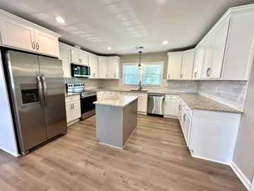 Taylors house for rent - A kitchen with white cabinets and a stainless steel refrigerator.