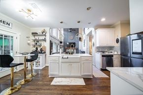 Midland house for rent - A kitchen with white cabinets and a black fridge.