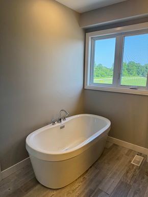 London house for rent - A white bathtub with a silver faucet is in a bathroom with a window.