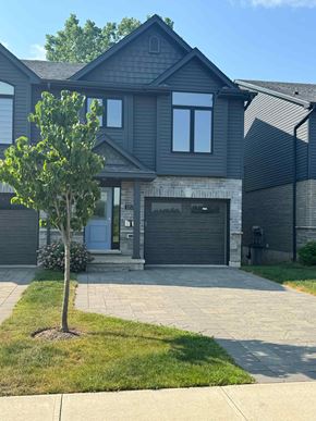 London house for rent - A house with a grey garage door and a tree in front.