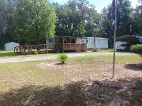 Interlachen house for rent - A small wooden building with a porch is surrounded by trees and a grassy area.
