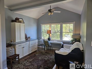 Raleigh house for rent - A living room with a black couch and a fan.