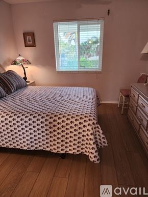 Naples condo for rent - A bedroom with a bed, a nightstand with a lamp, and a window with blinds.