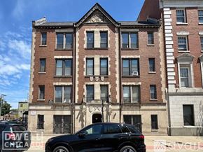 Chicago apartment for rent - A black SUV is parked in front of a red brick building.