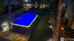Big Pine Key house for rent - A swimming pool lit up at night with a stone wall surrounding it.