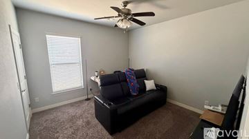 Bentonville house for rent - A living room with a black couch and a ceiling fan.