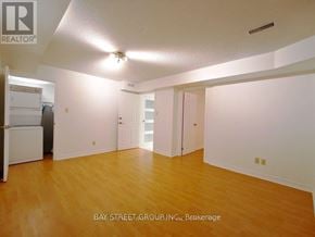 Toronto (Rouge) house for rent - A spacious room with wooden flooring and white walls.