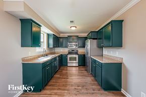 Clarksville house for rent - A kitchen with dark green cabinets and a wooden floor.