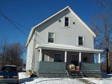 Lansing apartment for rent - A house with a blue car parked in front of it.