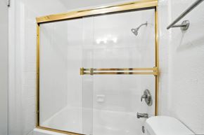 Vallejo apartment for rent - A white bathroom with a gold shower door.