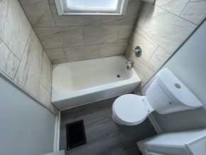 Louisville house for rent - A bathroom with a white toilet and a bathtub with a skylight above it.