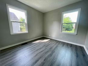 Louisville house for rent - A room with grey walls and wooden flooring with two windows.