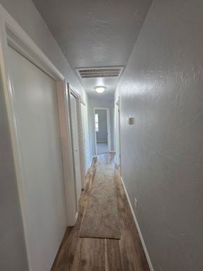 Harrah house for rent - A long, narrow hallway with a rug on the floor and doors on the left side.
