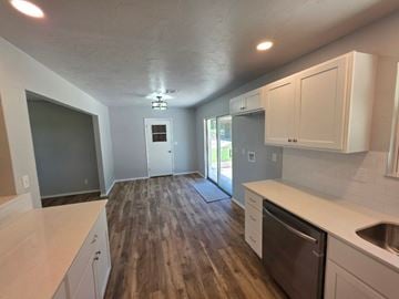 Harrah house for rent - A kitchen with white cabinets and a wooden floor.