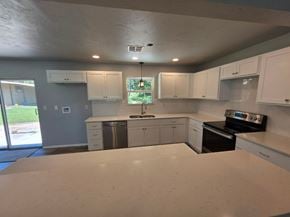 Harrah house for rent - A kitchen with white cabinets and appliances is shown.