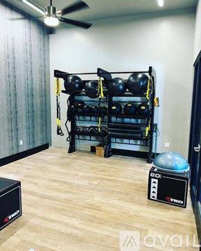 Salt Lake City apartment for rent - A gym room with a wooden floor, a wall-mounted rack with black weight plates, a fan, and a black device on the floor.
