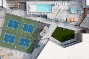 Salt Lake City apartment for rent - A tennis court is surrounded by a pool and a green area.