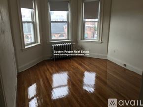 Boston apartment for rent - A room with wooden floors and three windows.
