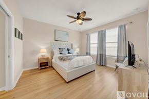 Bradenton condo for rent - A bedroom with a large bed, a ceiling fan, and a television.