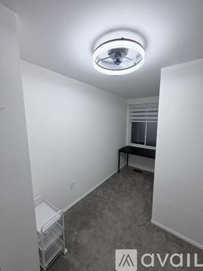 Ellicott City apartment for rent - A white chair is placed in a corner with a black desk and a window.