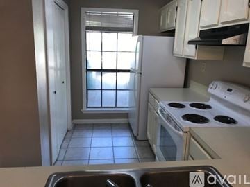 Broussard townhouse for rent - A kitchen with white appliances and a window with blinds.