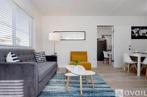 Miami apartment for rent - A grey couch with blue and white striped pillows sits in a room with a yellow chair and a white table.