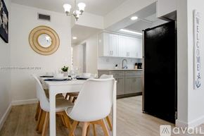 Miami apartment for rent - A kitchen with a white table and chairs and a black refrigerator.