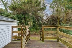 Richmond house for rent - A wooden bridge in a wooded area with a white building on the left.