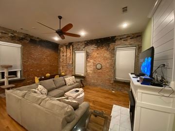 Jonesboro apartment for rent - A living room with a grey couch and a ceiling fan.