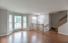 Bowie house for rent - A spacious room with wooden floors and a staircase.