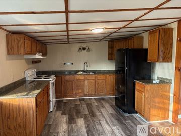 Rockport house for rent - A kitchen with wooden cabinets and a black refrigerator.