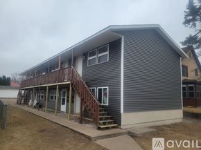 La Crosse apartment for rent - A grey house with a wooden deck and stairs leading to the entrance.