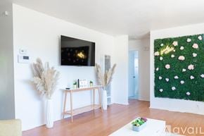 Joshua Tree house for rent - A living room with a flat screen TV mounted on the wall and a green wall hanging.