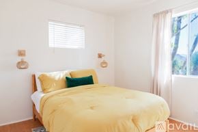 Joshua Tree house for rent - A bedroom with a bed covered in a yellow comforter and two green throw pillows.