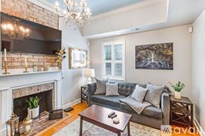 Savannah house for rent - A living room with a grey couch, a fireplace, and a chandelier.