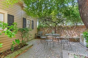 Savannah house for rent - A patio with a table and chairs is surrounded by a brick wall and trees.