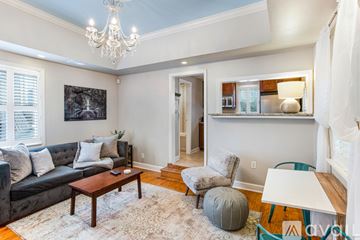 Savannah house for rent - A living room with a grey couch, a coffee table, a chair, a bean bag, a rug and a chandelier.