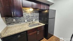 Dallas apartment for rent - A kitchen with dark wood cabinets and a black refrigerator.