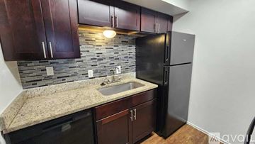Dallas apartment for rent - A kitchen with dark wood cabinets and a black refrigerator.